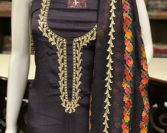 May include: A dark charcoal gray sleeveless tunic featuring intricate gold thread embroidery around the neckline. A matching dark charcoal gray scarf is draped over the shoulder, decorated with a vibrant floral border in orange, pink, and green.