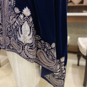 May include: A navy blue velvet shawl with silver embroidery. The shawl has a paisley design and is trimmed with a silver border.