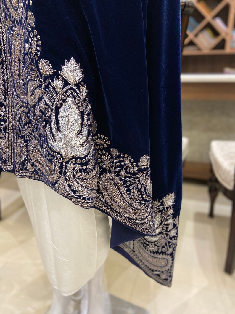 May include: A navy blue velvet shawl with silver embroidery. The shawl has a paisley design and is trimmed with a silver border.