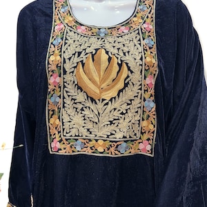 May include: A dark navy blue velvet tunic featuring a large rectangular chest panel with intricate gold thread embroidery of a central leaf motif surrounded by a border of colorful floral patterns in pink, blue, and yellow, with matching cuffs.