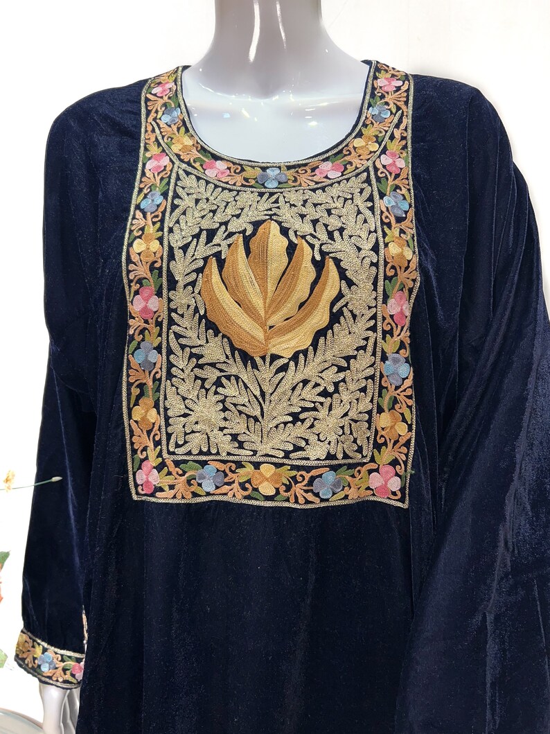 May include: A dark navy blue velvet tunic featuring a large rectangular chest panel with intricate gold thread embroidery of a central leaf motif surrounded by a border of colorful floral patterns in pink, blue, and yellow, with matching cuffs.