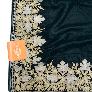 May include: A dark green velvet fabric with a gold and silver embroidered border. The border features a floral design with leaves and flowers.