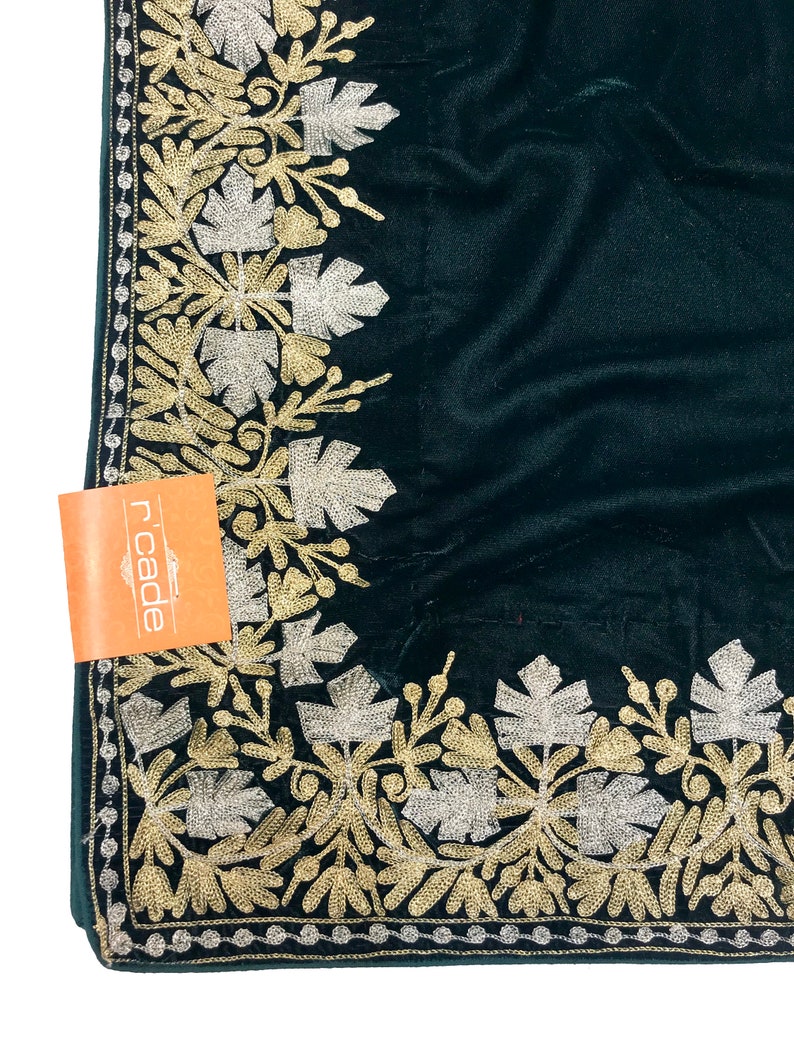 May include: A dark green velvet fabric with a gold and silver embroidered border. The border features a floral design with leaves and flowers.