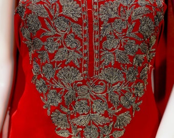 May include: A vibrant red tunic featuring an intricate, dark metallic floral embroidery pattern that extends from the neckline down the centre of the chest. The design includes detailed leaf and petal motifs crafted with fine, textured thread work.