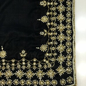 Puede incluir: Tela de terciopelo negro con un borde de cuentas doradas y blancas. El borde presenta un patr&oacute;n repetitivo de peque&ntilde;as flores y estrellas.