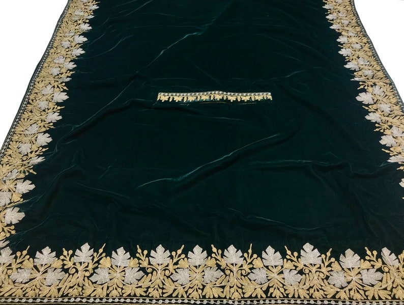 May include: A dark green velvet fabric with a gold and silver embroidered border. The border features a repeating pattern of leaves and flowers.