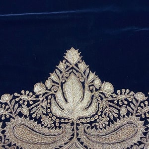 May include: A dark blue velvet fabric with a silver embroidered border. The border features a floral design with paisley shapes.