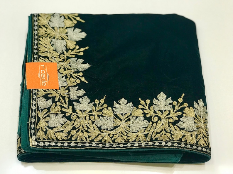 May include: A dark green velvet shawl with a gold and silver embroidered floral border. The shawl is folded and the brand name "ricade" is visible on a small orange tag.