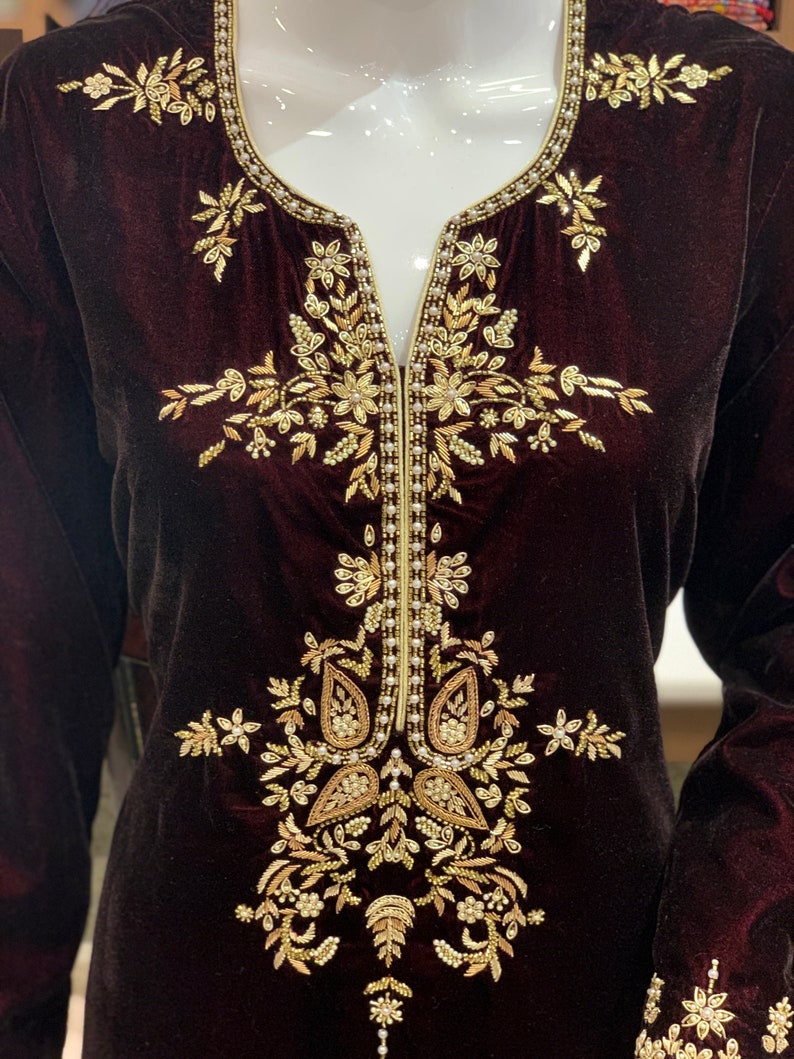 May include: A maroon velvet tunic with gold and pearl embroidery. The embroidery features a floral design with paisley shapes.
