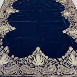 May include: A dark blue velvet shawl with a gold embroidered border. The border features intricate floral and paisley designs.