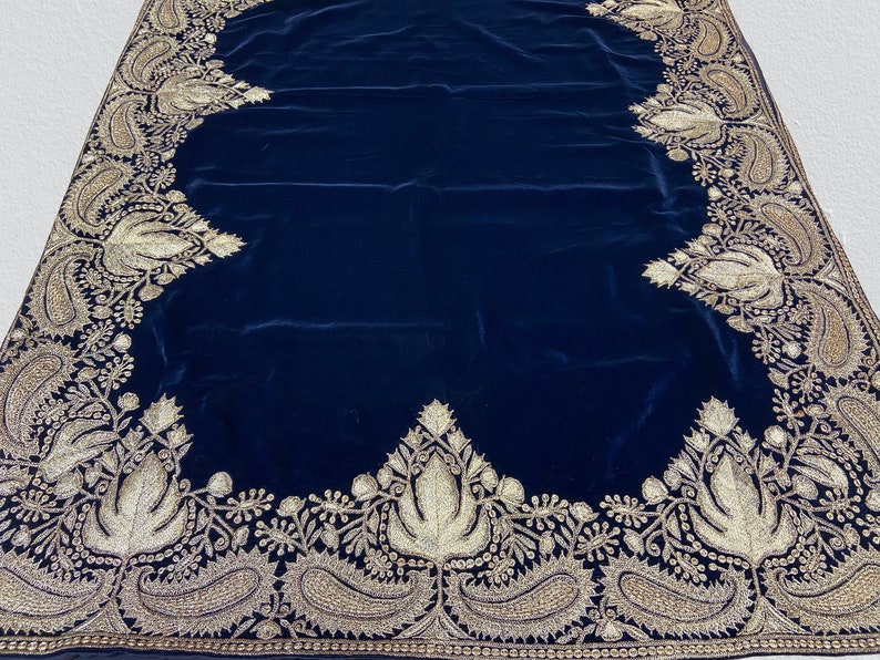 May include: A dark blue velvet shawl with a gold embroidered border. The border features intricate floral and paisley designs.
