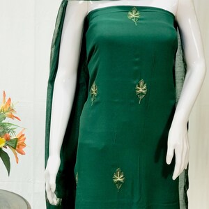 May include: A dark green dress with a leaf pattern embroidered on it. The dress is made of a soft, flowing fabric and has a simple, elegant design.