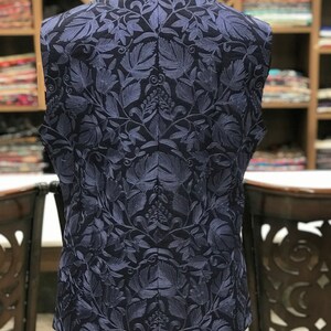 Pu&ograve; includere: Un gilet blu navy senza maniche con un motivo di ricamo floreale.