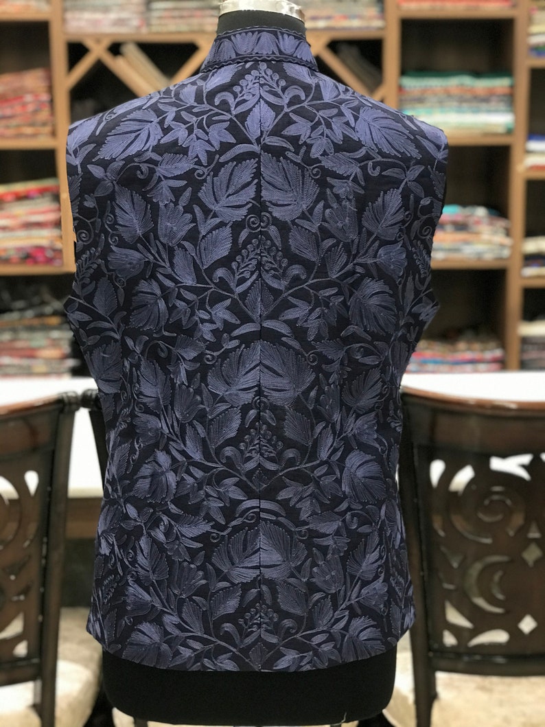 Pu&ograve; includere: Un gilet blu navy senza maniche con un motivo di ricamo floreale.