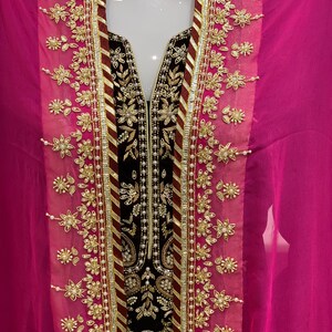 May include: A black velvet dress with gold and white embroidery. The dress has a V-neckline and is paired with a pink chiffon dupatta.