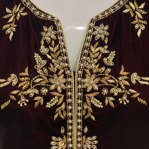 May include: A dark brown velvet fabric with gold and white embroidery. The embroidery features a floral design with leaves and flowers.