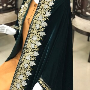 May include: A dark green velvet shawl with gold and silver embroidery. The shawl has a floral design and is trimmed with a gold and silver border.