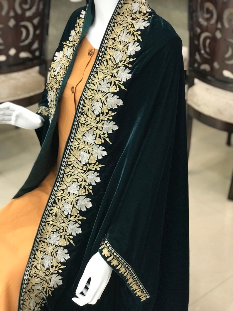 May include: A dark green velvet shawl with gold and silver embroidery. The shawl has a floral design and is trimmed with a gold and silver border.