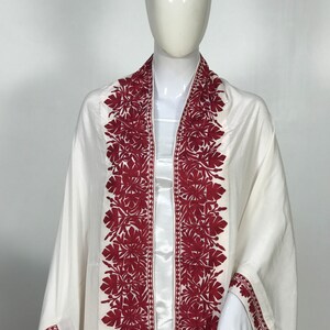 May include: White shawl with red embroidered floral designs along the edges.