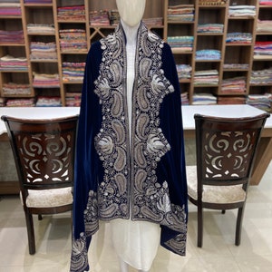 May include: A navy blue velvet shawl with silver embroidery. The shawl has a paisley pattern and is draped over a white dress form.