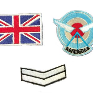 Könnte beinhalten: Drei gestickte Patches: eine Union Jack Flagge, ein blauer und weißer runder Patch mit einem roten Kreis und dem Wort "TRACER" und ein weißer Chevron Patch.