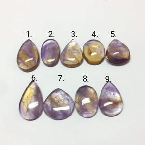Puede incluir: Nueve piedras de amatista en forma de l&aacute;grima con una mezcla de tonos morados y amarillos. Las piedras est&aacute;n numeradas del 1 al 9.