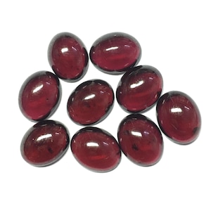 Może przedstawiać: Dziewięć owalnych, ciemnoczerwonych kamieni szlachetnych. Kamienie szlachetne są gładkie i wypolerowane, z błyszczącym wykończeniem.