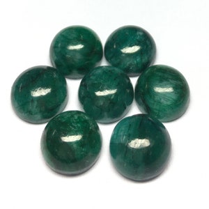 Può includere: Sette pietre preziose rotonde e lucide, di colore verde smeraldo, sono disposte su una superficie bianca. Le pietre hanno una finitura liscia e lucida, che riflette la luce. Le pietre sono di un verde intenso, con sottili variazioni di tono.