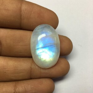Op de afbeelding: Ovaalvormige maansteen cabochon met een witte basis en iriserende blauwe en groene flitsen.