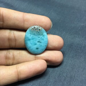 May include: Oval shaped blue and brown gemstone cabochon with a marbled pattern.