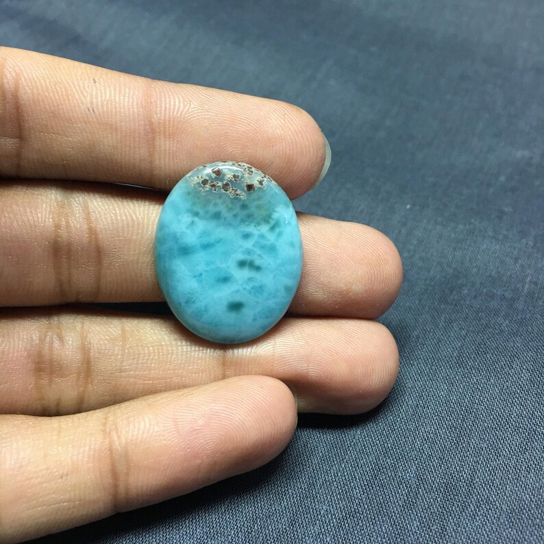 May include: Oval shaped blue and brown gemstone cabochon with a marbled pattern.