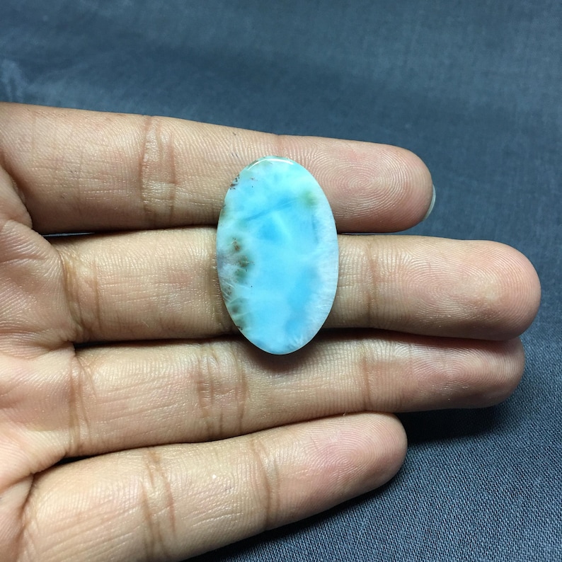 May include: Oval shaped blue and green gemstone cabochon with white and gray markings.