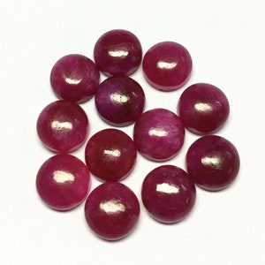 May include: Twelve round, cabochon cut, pink gemstones. The gemstones are smooth and polished.