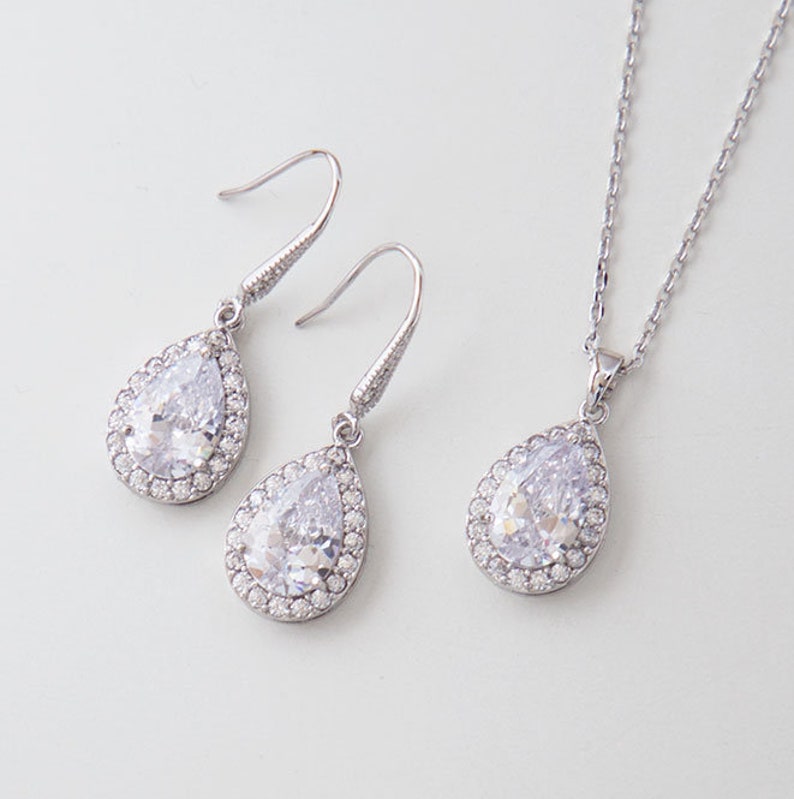 Pu&ograve; includere: Una collana con ciondolo a forma di lacrima e orecchini abbinati in argento con pietre di zircone cubico trasparenti.