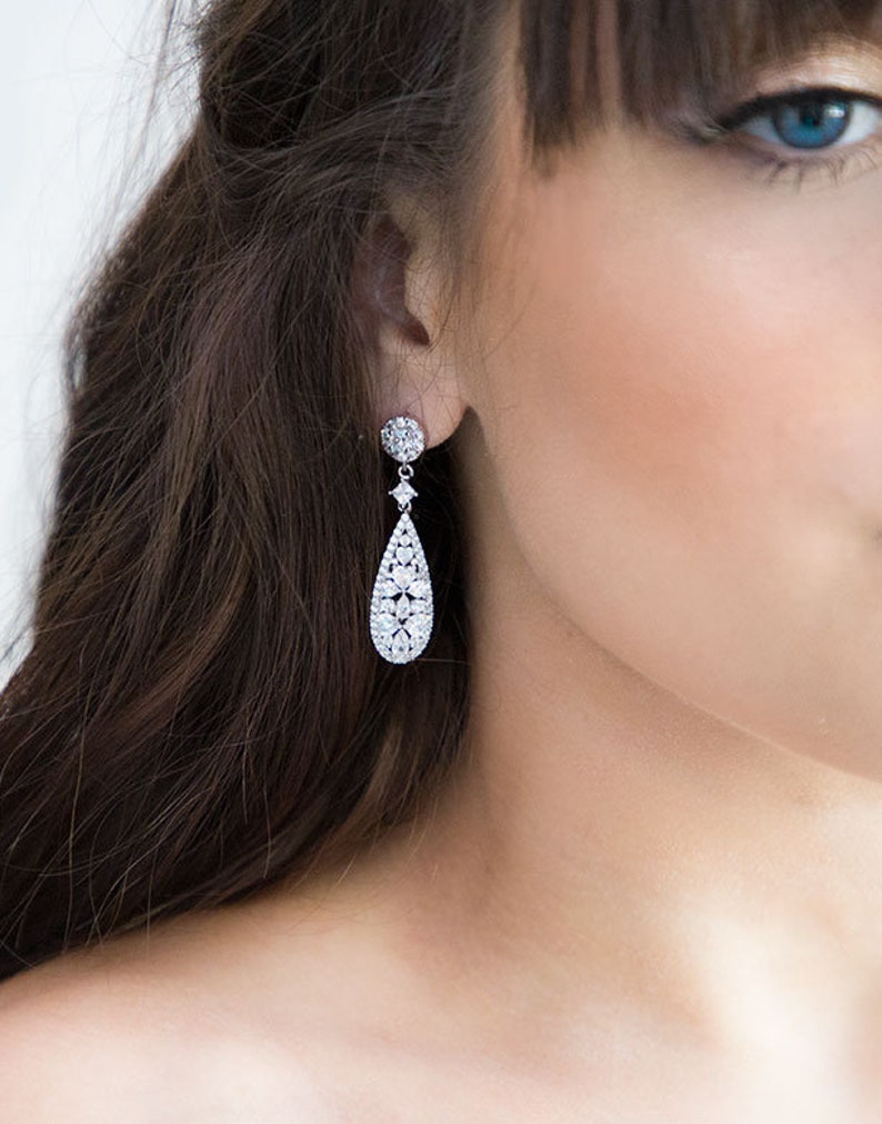 May include: Silver teardrop earrings with a cluster of clear cubic zirconia stones.