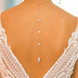 May include: A delicate back necklace with a gold chain and small crystal accents in the shape of leaves.