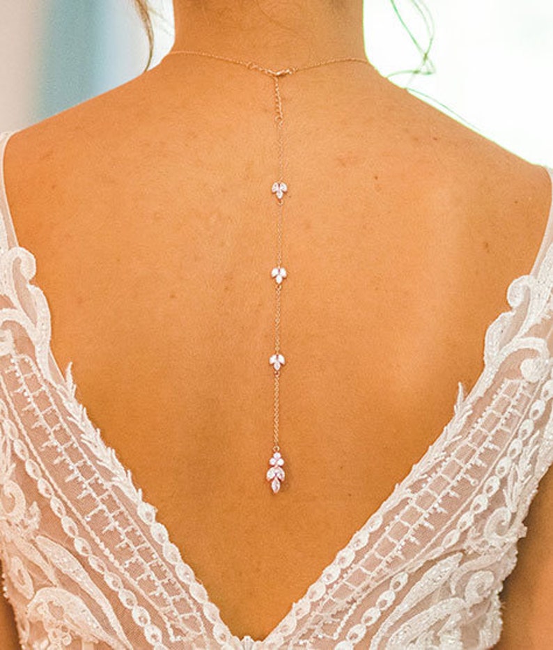 May include: A delicate back necklace with a gold chain and small crystal accents in the shape of leaves.