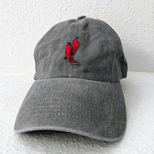 May include: A gray, washed cotton baseball cap with a red chili pepper embroidered on the front.