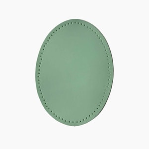 Op de afbeelding: Een lichtgroene ovale leren patch met een decoratieve steek rond de rand.