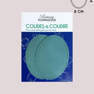 Può includere: Due toppe per gomiti in pelle blu turchese con bordo cucito. Le toppe hanno un diametro di 8 cm. La confezione ha il testo "Britney Pompadour" e "Coudes à Coudre" in nero su sfondo blu.