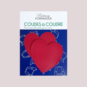 Op de afbeelding: Twee rode hartvormige elleboogpatches met stiksels rond de randen. De patches bevinden zich op een blauwe achtergrond met de tekst "Britney Pompadour Coudes à Coudre Beaucoup plus jolis qu'un trou" in wit.