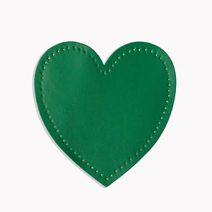 May include: A green leather heart-shaped patch with a decorative stitch around the edge.