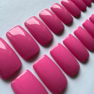 May include: A set of pink press-on nails in various sizes. The nails are square shaped and have a glossy finish.