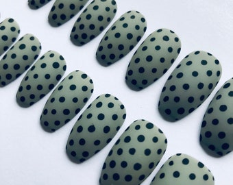 May include: Set of ten green and black oval-shaped press-on nails with black polka dots.