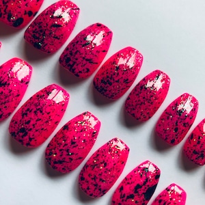 Uñas postizas cortas tipo ataúd con salpicaduras de pintura rosa neón.