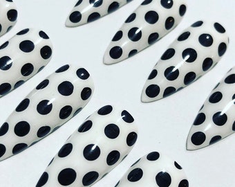 May include: Set of white stiletto false nails with black polka dots.