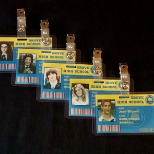 May include: Five blue and yellow Grove High School ID cards with student photos and information. The cards have a clear plastic cover and a metal clip.