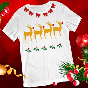May include: White t-shirt with a Christmas design featuring four reindeer with red noses and holly leaves. The reindeer are in a line and are facing to the right. The shirt has a white background and the design is in red, green, and yellow.