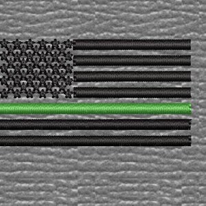 Op de afbeelding: Een Amerikaanse vlag met een groene streep in het midden, die de dunne groene lijn voorstelt, een symbool van steun voor de rechtshandhaving.