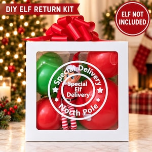 Puede incluir: Una caja de regalo cuadrada blanca con un lazo rojo encima, que contiene globos rojos y verdes y una pequeña muñeca de elfo. La caja presenta una etiqueta blanca circular con el texto Special Delivery Special Elf Delivery North Pole.